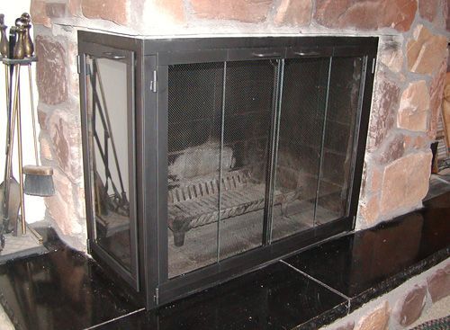 A fireplace with a screen and a fire in it.