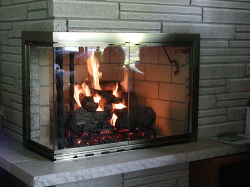A fireplace with a glass door and a brick wall