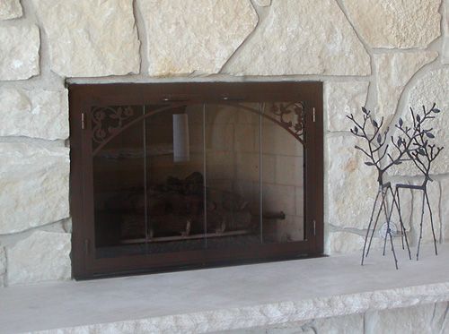 A fireplace with a glass door and a deer statue on the mantle.