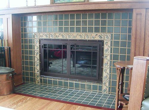 A fireplace in a living room with green tiles