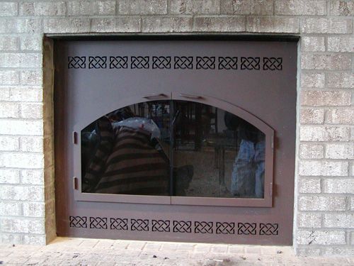 A fireplace in a brick wall with a glass door