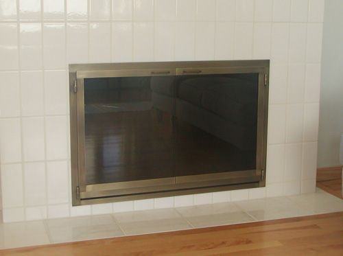 A white tiled fireplace with a black screen