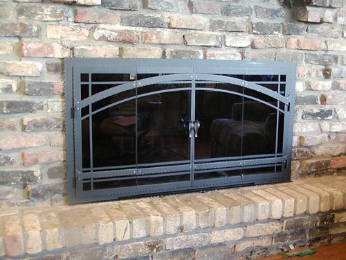 A fireplace with a black screen and a brick wall