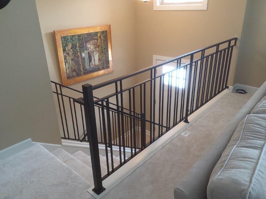 A staircase with a railing and a painting on the wall.