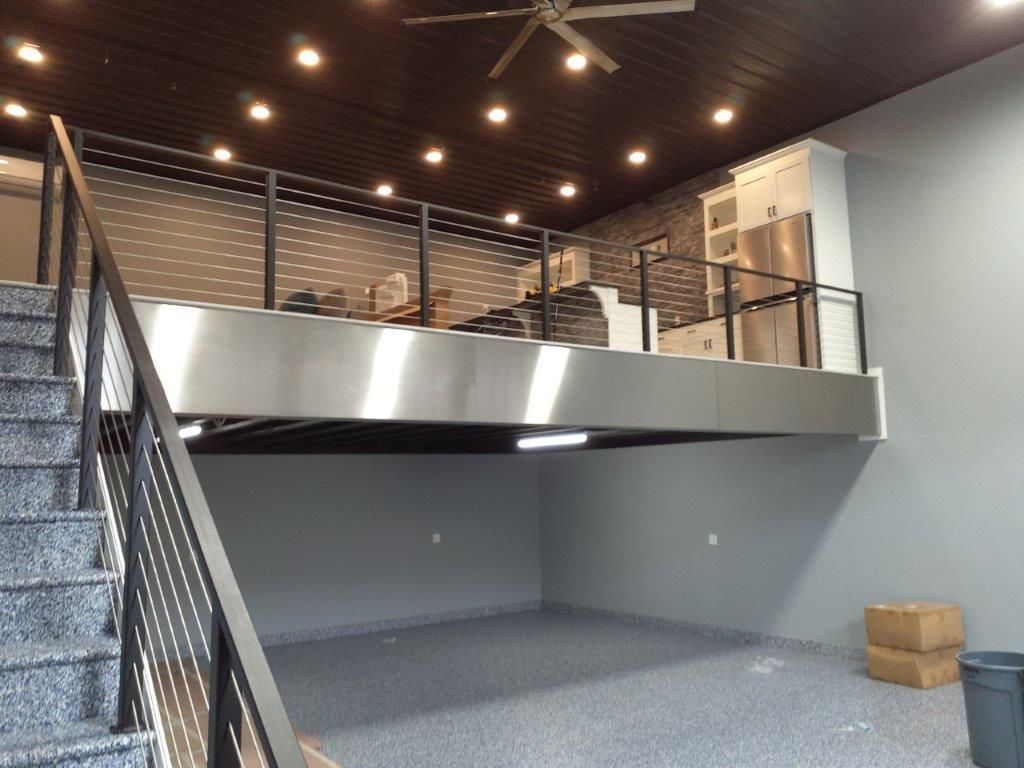 A room with stairs leading up to a balcony and a ceiling fan