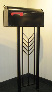 A black mailbox with a red handle is sitting in a corner of a room.