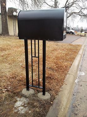 A black mailbox is sitting on the side of the road.