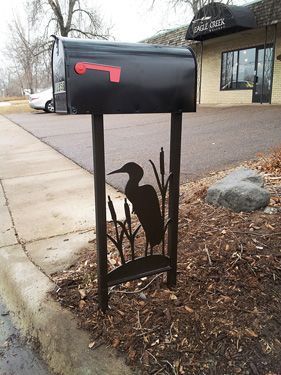 A black mailbox with a bird on it in front of a building