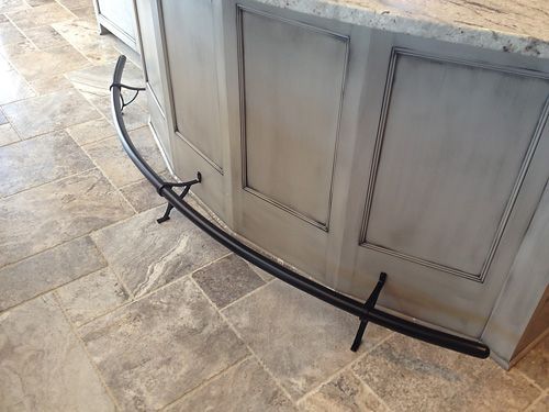 A metal bar is sitting on a tiled floor next to a counter.