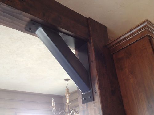 A black metal bracket is attached to a wooden wall