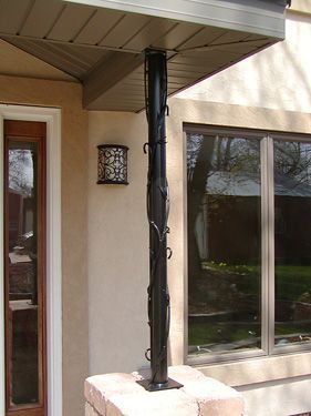 A porch with a black pole and a lamp on it