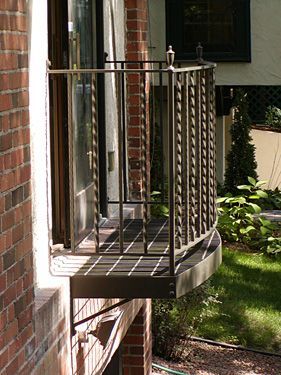 There is a balcony on the side of a brick building.