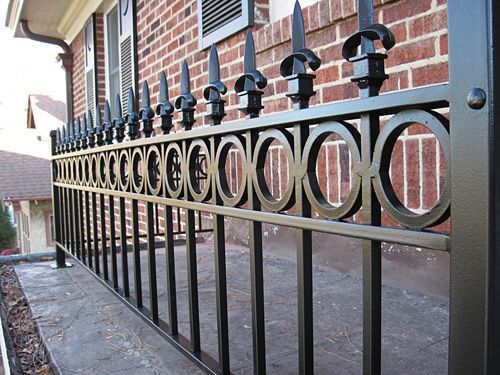 A wrought iron fence with a brick building in the background