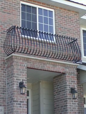 A brick building with a balcony with a wrought iron railing