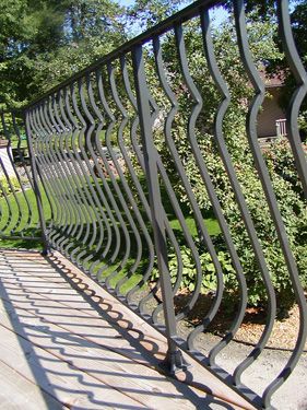 A wrought iron railing on a balcony with trees in the background