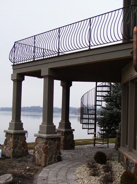 A spiral staircase leads to a balcony overlooking a lake