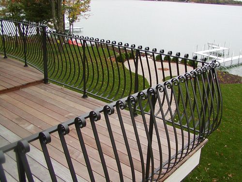 A wrought iron railing on a deck overlooking a lake