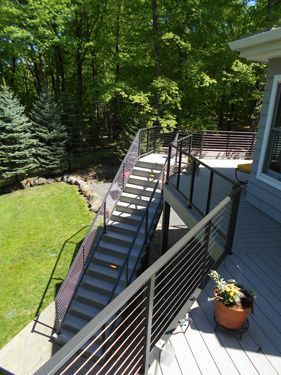 A deck with stairs leading up to a lush green yard.