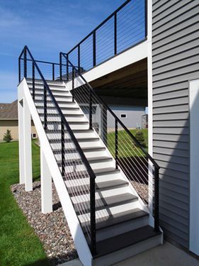 A set of stairs leading up to a deck with a black railing.