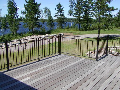 A wooden deck with a metal railing overlooking a lake