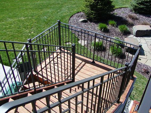 A wooden deck with a metal railing and stairs leading up to it.