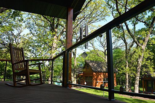 A rocking chair is sitting on a porch with a glass railing.