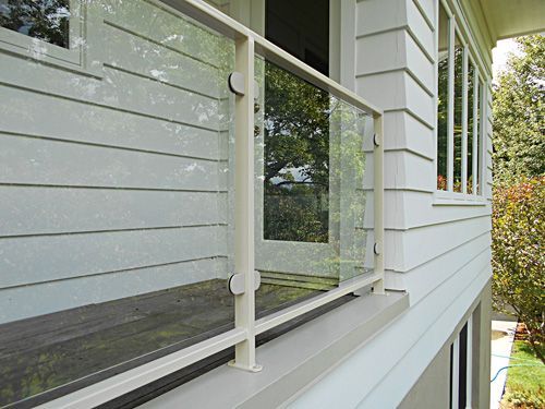 A white house with a glass railing on the porch.
