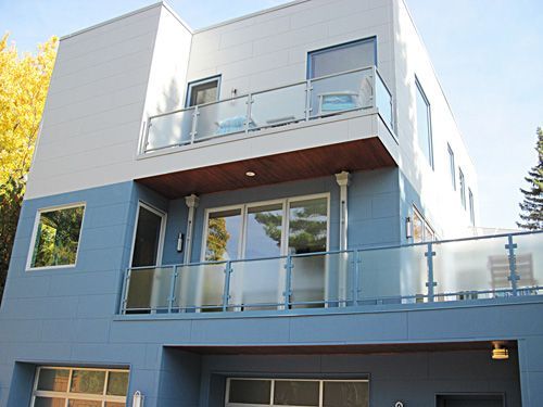 A blue and white house with a balcony and glass railing