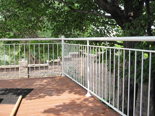 A white railing on a deck with trees in the background