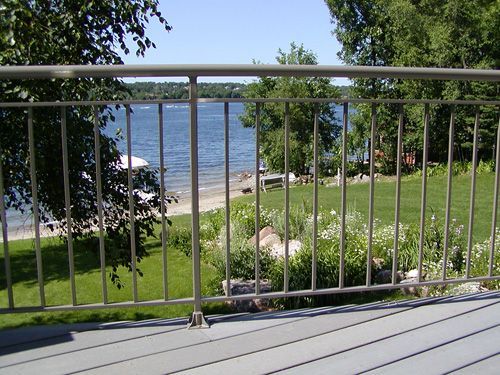 A view of a lake from a deck with a metal railing