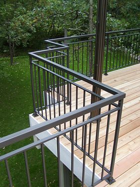 A wooden deck with a metal railing and stairs leading up to it.