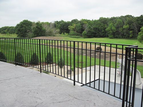 A view of a golf course from a balcony with a metal railing