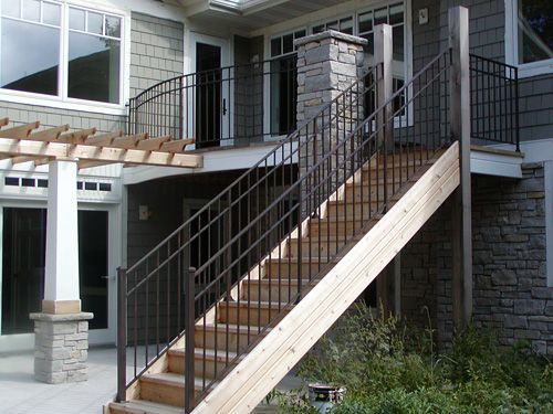 A wooden staircase with a metal railing leading up to a house