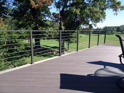 A wooden deck with a metal railing and a chair on it.