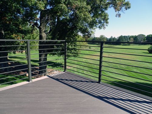 A balcony overlooking a golf course with trees in the background
