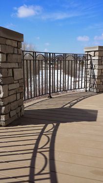 A balcony with a wrought iron railing and a stone wall.