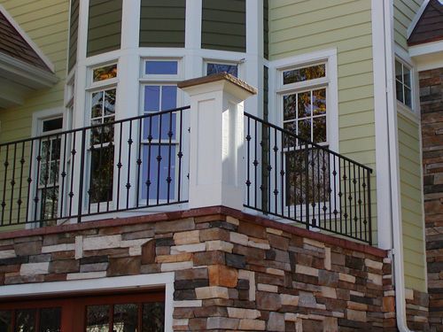 A house with a balcony and a stone wall