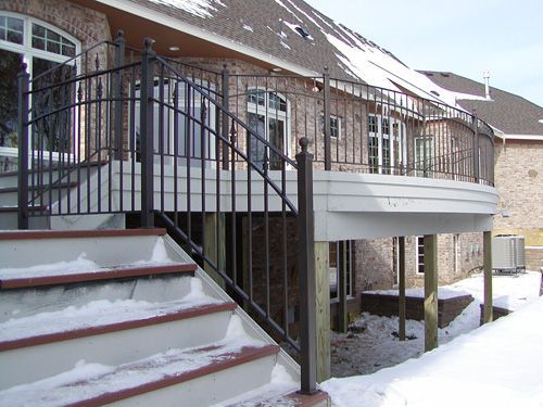 A house with a deck and stairs in the snow