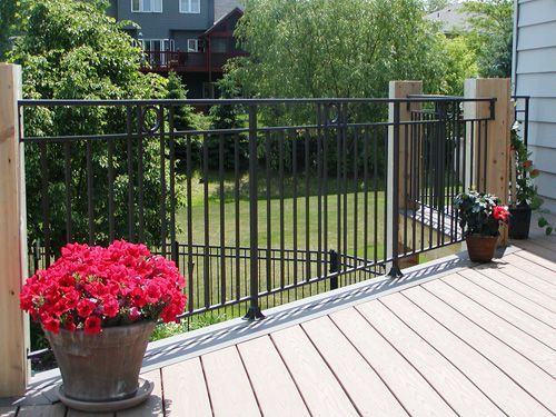 A deck with a fence and a pot of red flowers