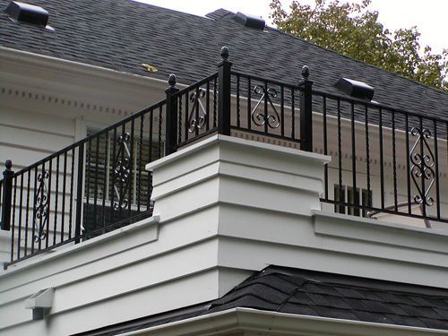 A balcony on the side of a house with a black railing