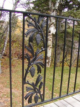 A wrought iron railing with pine cones and leaves on it