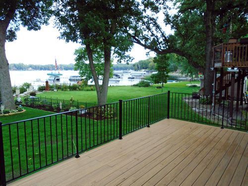 A wooden deck with a metal railing overlooking a lake