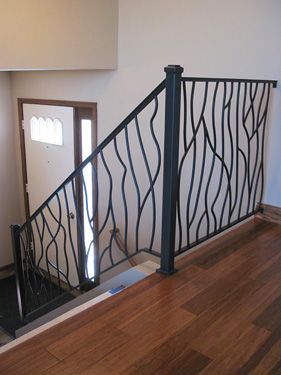 A staircase with a wrought iron railing and a wooden floor.