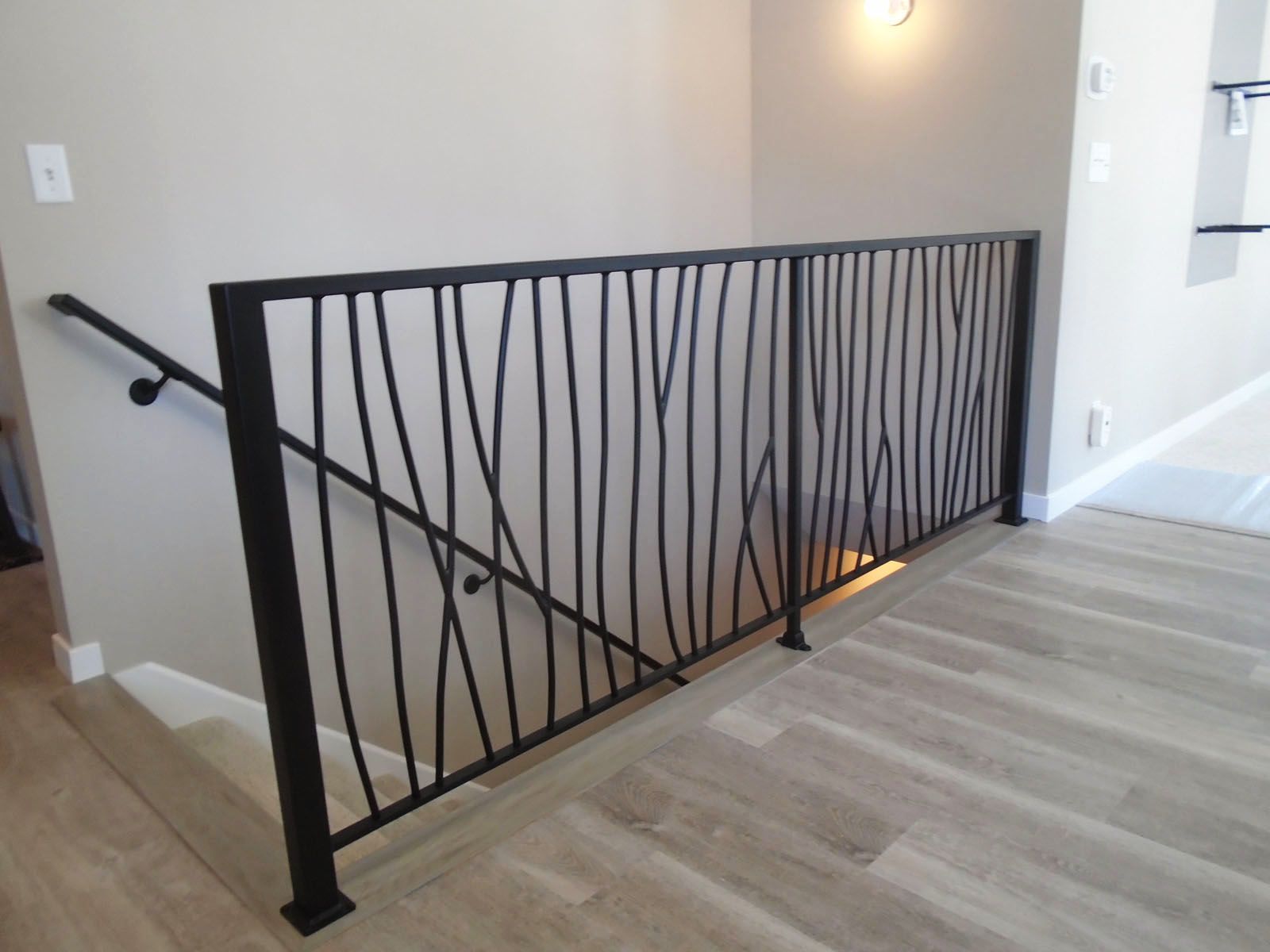A staircase with a black railing and a wooden floor