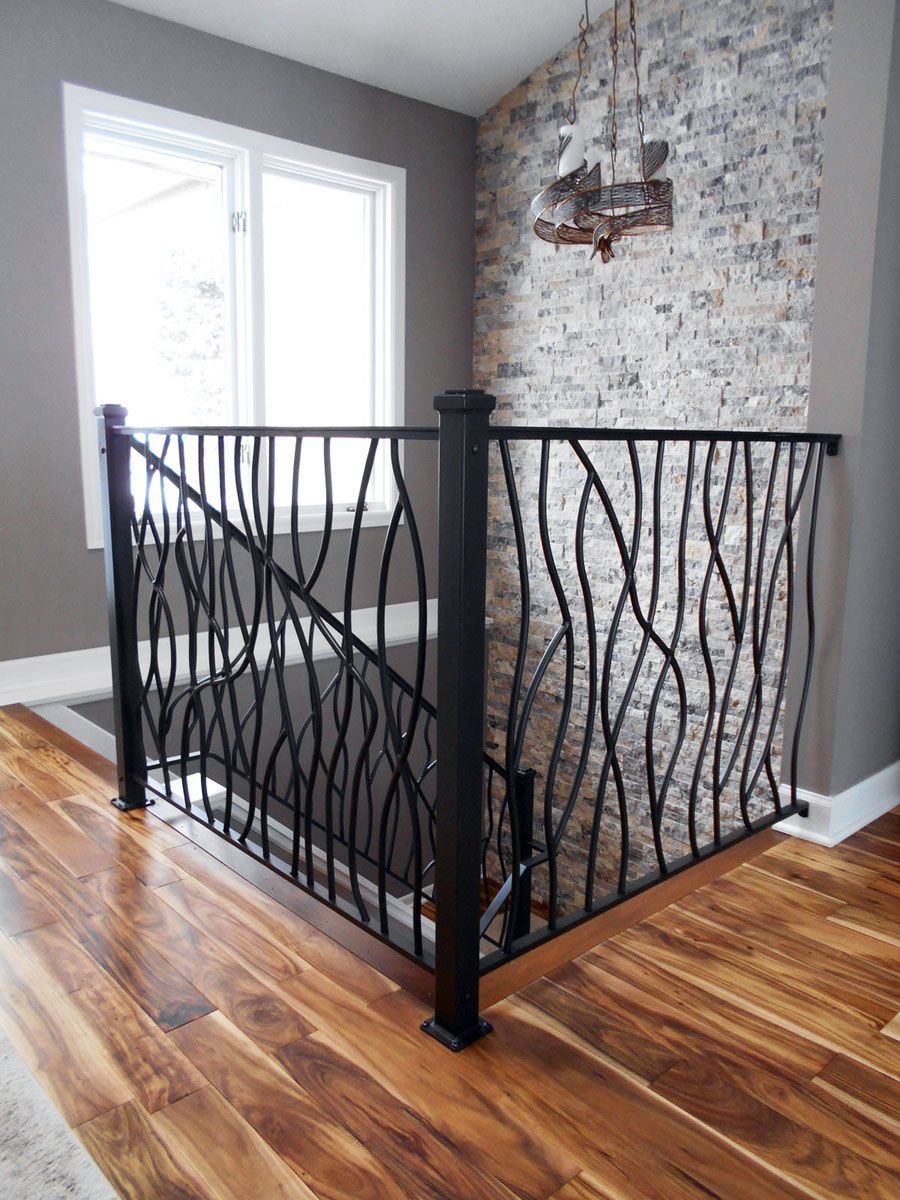 A staircase with a wrought iron railing and a wooden floor