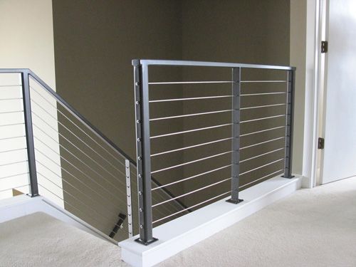 A staircase with a stainless steel railing and a white door