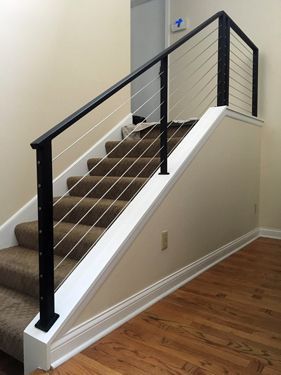 A staircase with a black railing and a brown carpet.