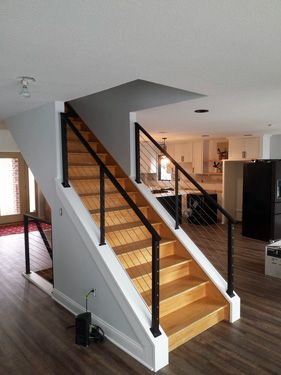 A wooden staircase with a black railing in a house
