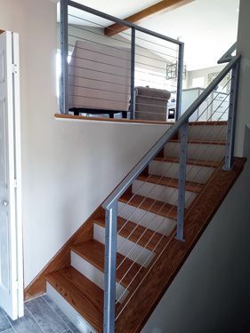 A staircase with a metal railing and wooden steps in a house.