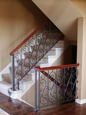 A staircase with a wrought iron railing and wooden handrail